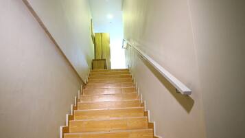 Una escalera de madera con barandilla que lleva a un rellano con una lámpara.