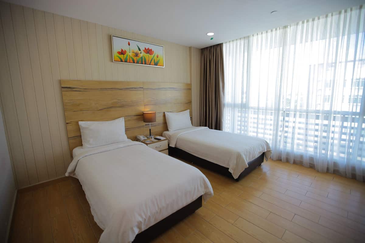 Ein Hotelzimmer mit zwei Betten, einem Holzkopfende, einem Nachttisch mit Lampe und einem Bild an der Wand.