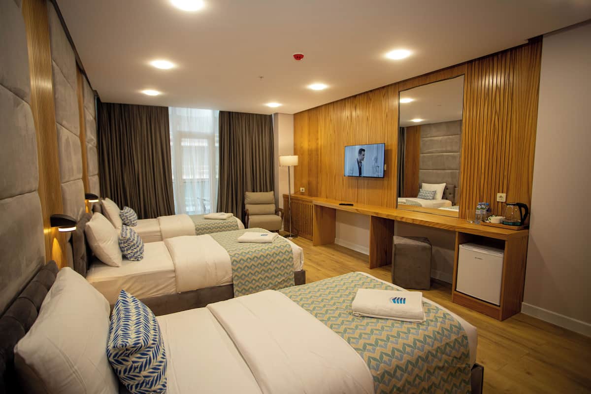Habitación de hotel con dos camas, un escritorio, un televisor y un refrigerador pequeño.