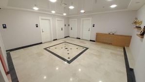 A spacious room with a marble floor, white walls, and multiple doors.