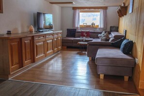 A living room with a sofa set, wooden cabinets, a television, and a window with curtains. - Chalet near Passthurn Ski Area Kitzbühel (Mittersill)