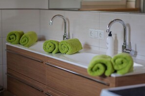 A bathroom with a white sink, two faucets, and green towels rolled up on the counter. - Chalet near Passthurn Ski Area Kitzbühel (Mittersill)