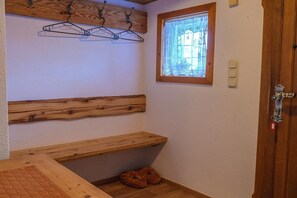 A room with a wooden bench, a window with lace curtains, and a door with a lock.