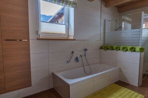 A bathroom with a bathtub, a window, and a shower area.