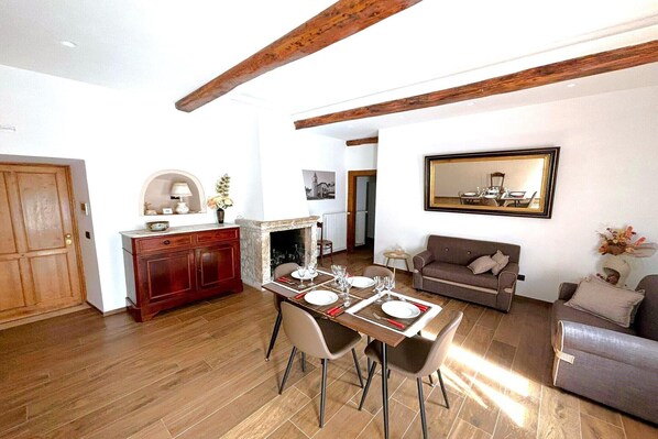 A dining area with a wooden table set for four, a sofa, and a fireplace.