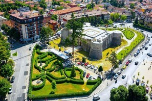 An aerial view of a historic building with a central courtyard, surrounded by modern buildings and a busy street.