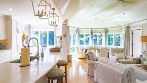 A spacious kitchen with a large island, bar stools, and a view of the outdoors.