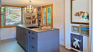 Een keuken met een vast kookeiland, een kroonluchter en kunstwerken aan de wanden.