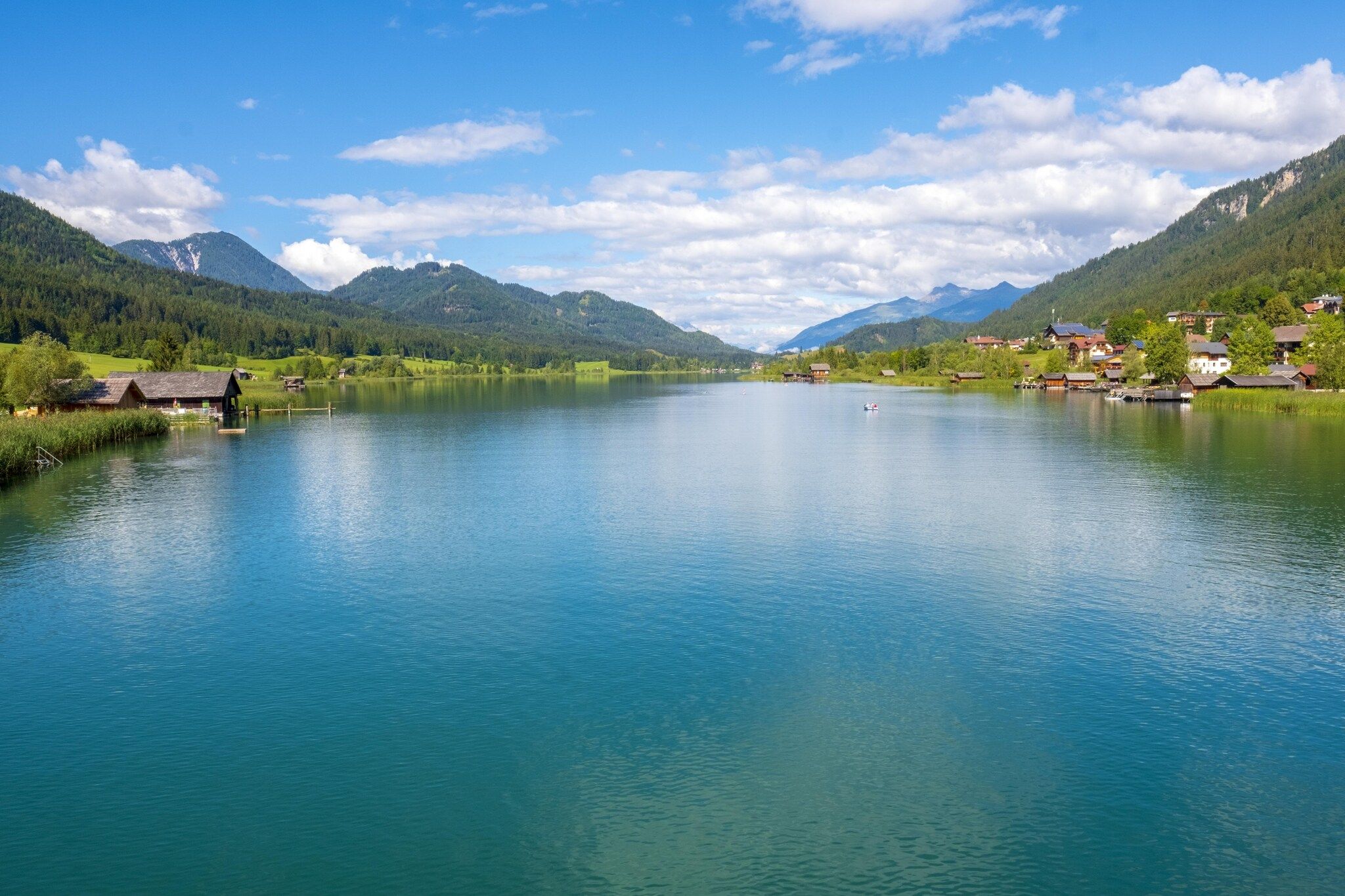 Un lac paisible, bordé d’un village et entouré de montagnes.