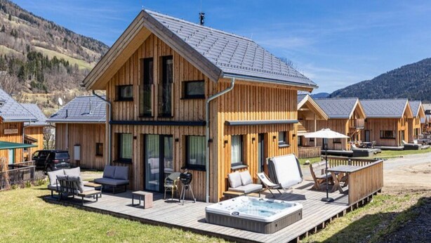 A wooden lodge with a hot tub and outdoor seating.