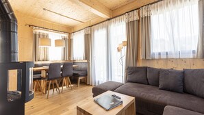 A cozy cabin interior with a wooden dining area, a sofa, and a fireplace.