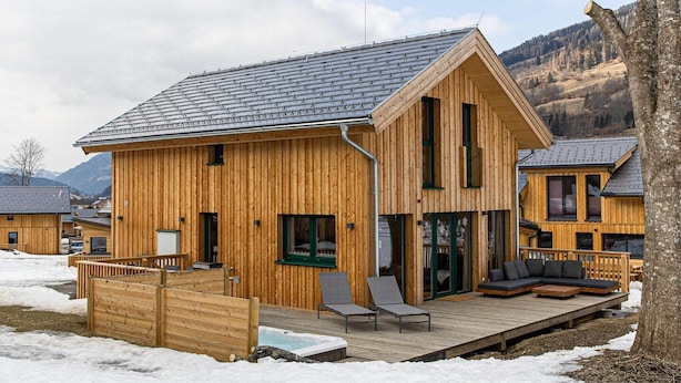 Eine Holzhütte mit einer Terrasse, großen Fenstern und Bergblick.