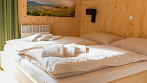 Ein ordentlich bezogenes Bett mit weißen Leinen und einem gefalteten Handtuch, ein Landschaftsbild an der Wand und ein hölzernes Kopfteil.