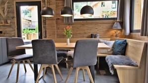 A modern dining area with a wooden table, grey upholstered chairs, and a bench with cushions. - Attractive chalet with sauna (Sankt Georgen am Kresichberg)