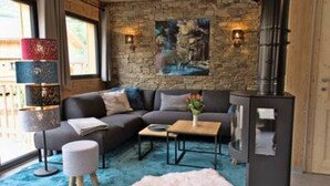 A cozy living room with a stone wall, a fireplace, a sofa, and a coffee table. - Attractive chalet with sauna (Sankt Georgen am Kresichberg)
