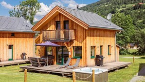Una cabaña de madera con balcón, mobiliario exterior y un jacuzzi.
