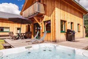 Une cabane en bois dotée d’un bain à remous, d’un espace salon extérieur et d’un barbecue.