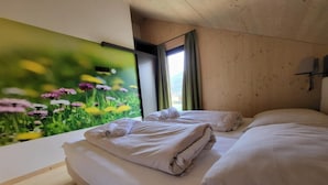 A room with two beds, a wooden ceiling, and a wall mural of flowers. - Beautiful chalet with sauna (Sankt Georgen am Kresichberg)