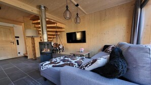 A cozy room with a sofa, a fireplace, a TV, and a wooden interior. - Beautiful chalet with sauna (Sankt Georgen am Kresichberg)