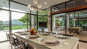 Un comedor moderno con una mesa de vidrio, sillas de metal y una cesta de frutas.
