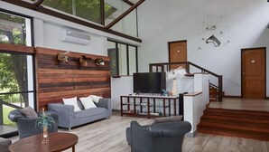 Una sala moderna con un sofá gris, una mesa redonda de centro y un mueble para la televisión.