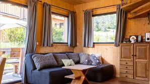 Interior acogedor de una cabaña con un sofá de madera, una mesita pequeña y un armario.