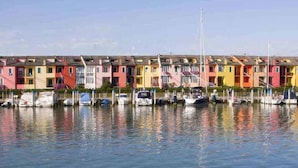 A row of colorful, multi-story buildings with a marina in front. - Apartment in Porto Santa Margherita (Porto Santa Margherita - Caorle)