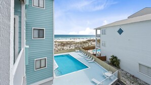 A pool with lounge chairs, a view of the beach, and a building with a balcony. - Romar Beach 203 (Orange Beach)