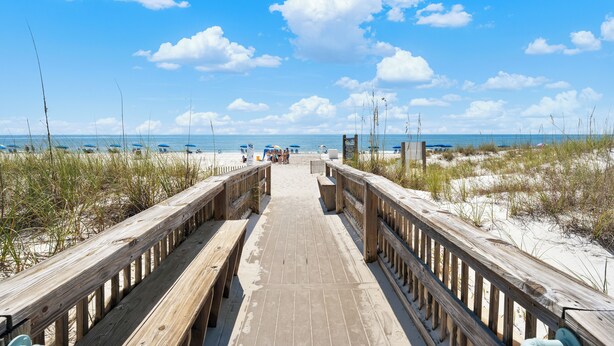 A wooden boardwalk leading to a beach with sand dunes and a clear blue sky. - Romar Beach 203 (Orange Beach)