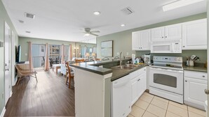 A modern kitchen with white cabinets, a built-in oven, and a large island with a sink. - Romar Beach 203 (Orange Beach)