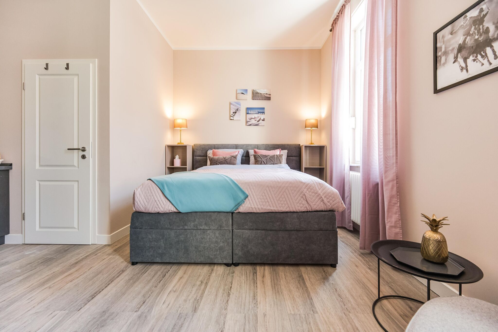 A bedroom with a bed, bedside tables, a door, and a small table with a pineapple decoration.