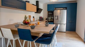 Una cocina moderna con una isla central, taburetes de bar y un refrigerador de acero inoxidable.