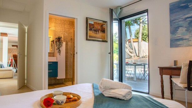 Una habitación de hotel con cama, bandeja de desayuno, un cuadro y vistas al exterior.