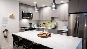 A modern kitchen with stainless steel appliances, a central island, pendant lighting, and a minimalist design.