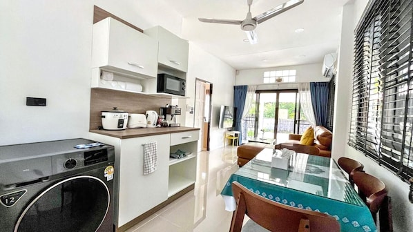 A modern kitchen with appliances, a dining area with a table and chairs, and a ceiling fan.