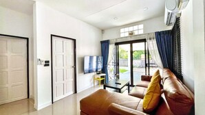 Una sala de estar moderna con sofá, televisor y puerta corrediza de vidrio que da a un balcón.