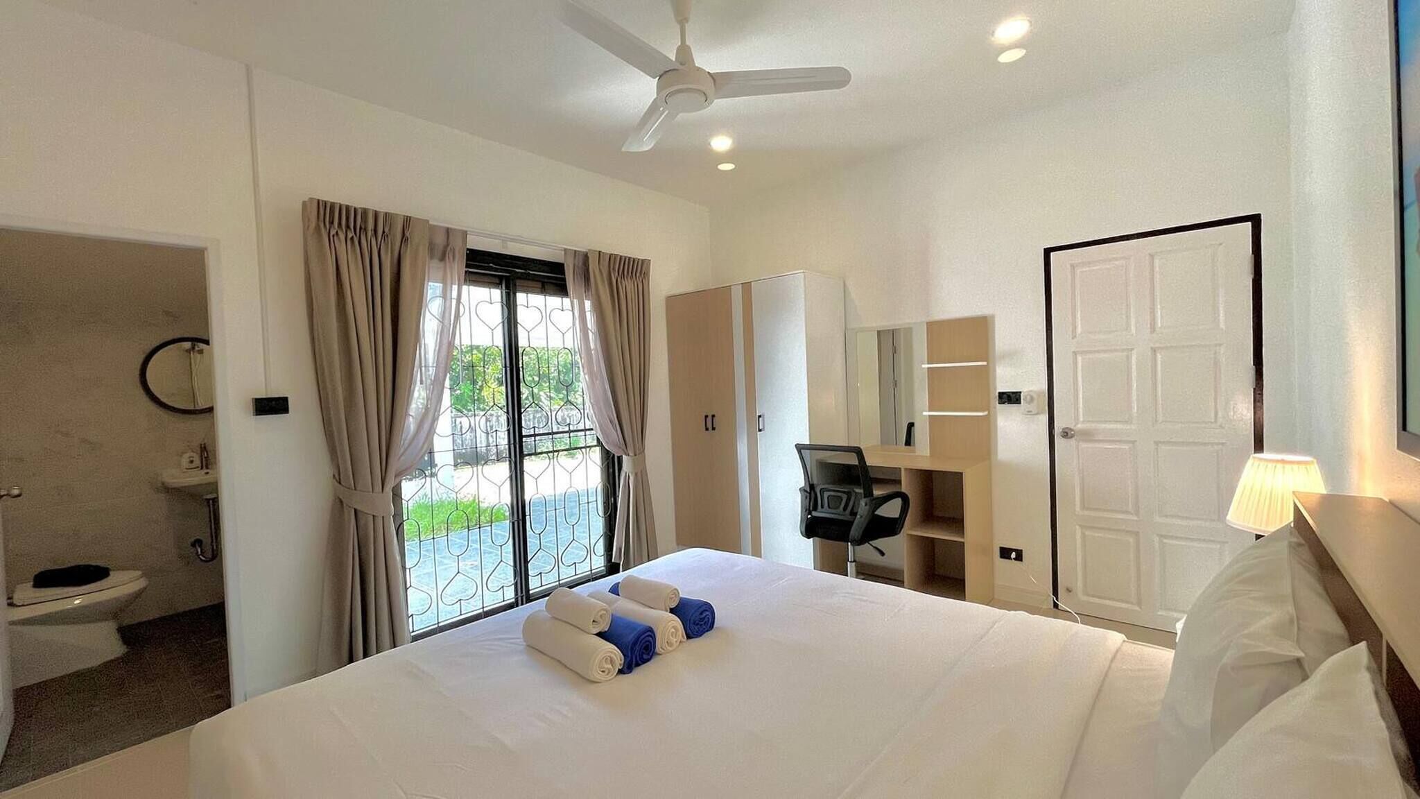 A hotel room with a bed, a desk, a chair, a wardrobe, a bathroom, and a door.