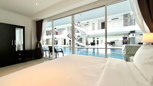 A hotel room with a large bed, a view of a swimming pool, and a balcony with a view of the pool area. - B12a - 2 Bdr Serviced Apt with Pool Access, Karon Beach (Tambon Karon)