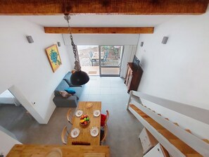 A modern interior with a dining area, a sofa, and a view to an outdoor patio. - Cosy apartment for 6 people with WIFI, TV, terrace and pets allowed (Mimizan)