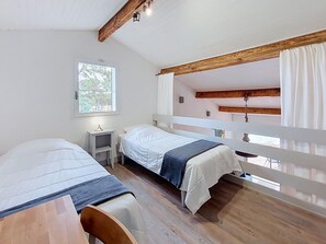 A room with two beds, a small table, a window with curtains, and a wooden ceiling. - Cosy apartment for 6 guests with WIFI, TV, terrace and pets allowed (Mimizan)