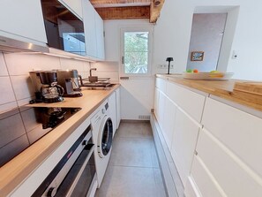 A compact kitchen with a coffee maker, a washing machine, and a window providing natural light. - Cosy apartment for 6 people with WIFI, TV, terrace and pets allowed (Mimizan)