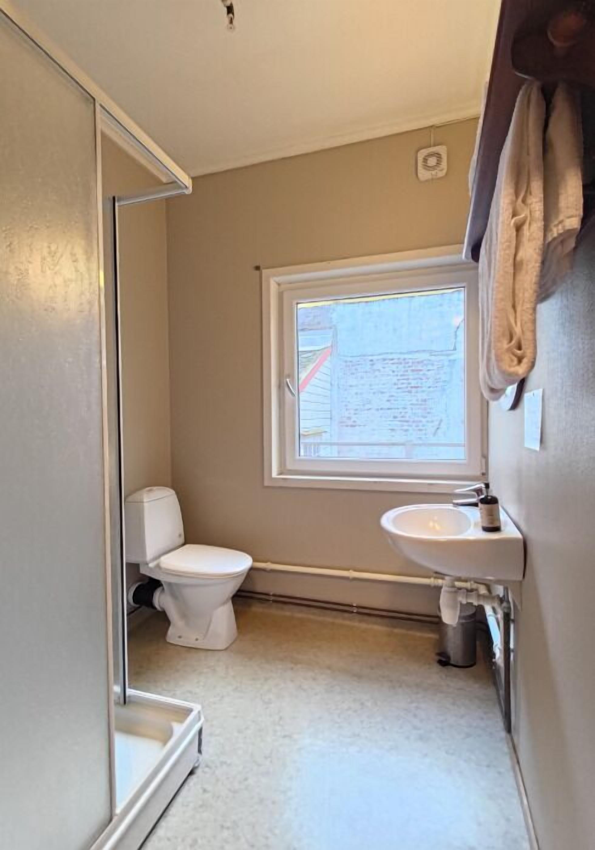 A small bathroom with a toilet, sink, and window.