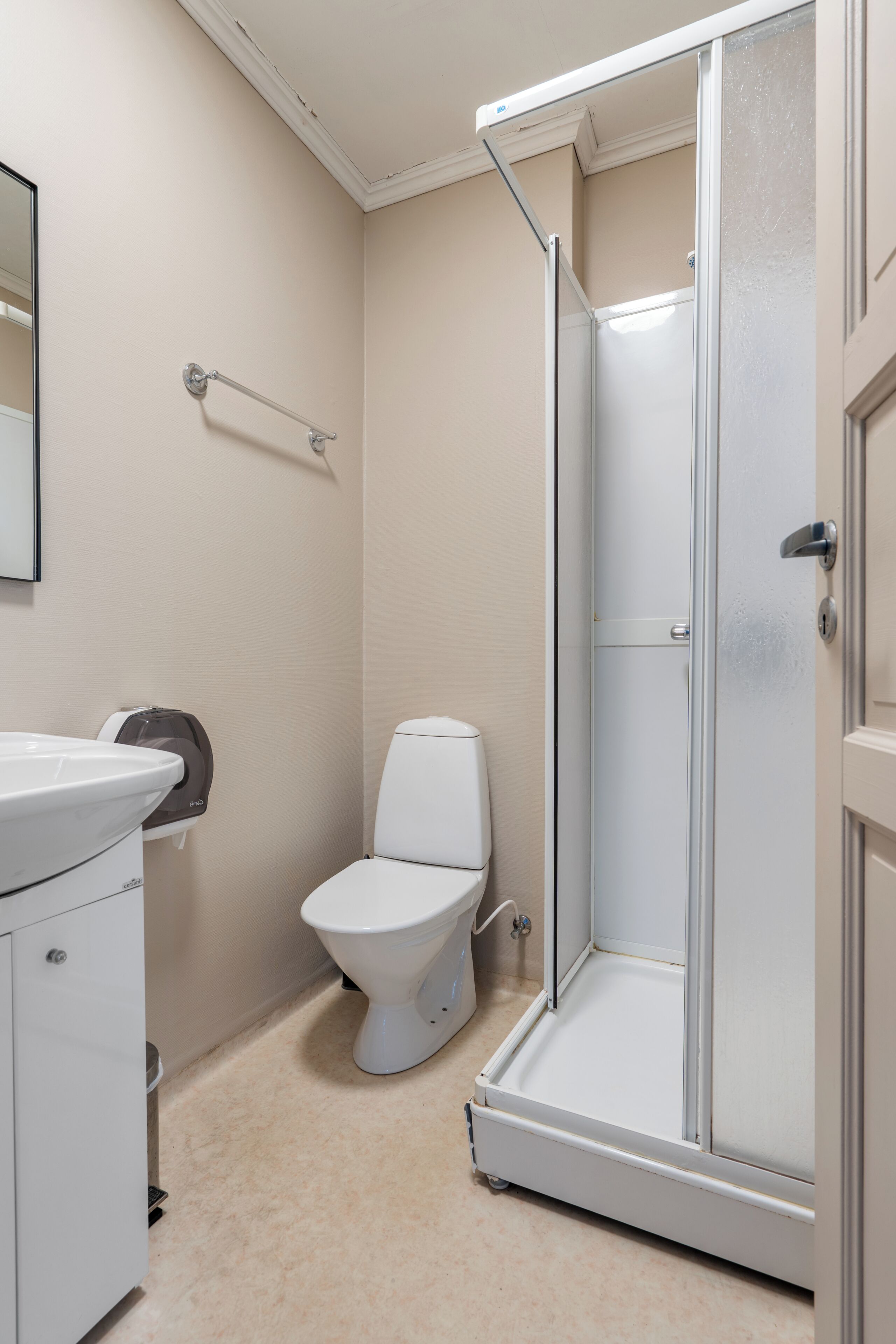 A bathroom with a toilet, a sink, a shower enclosure, and a mirror.