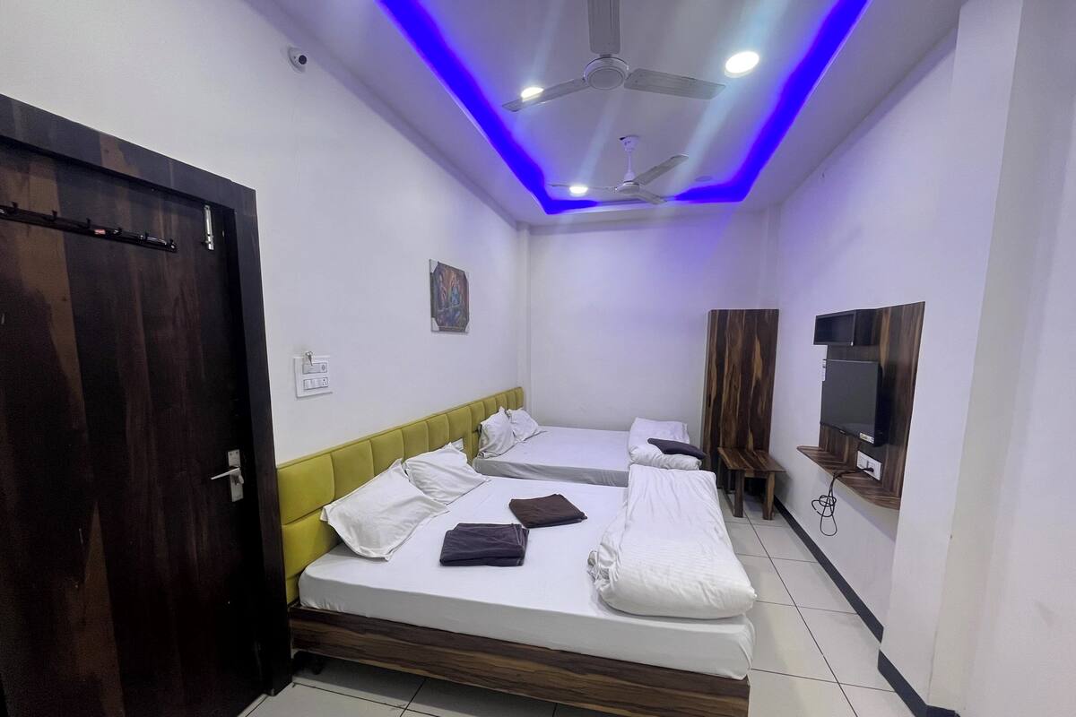 A hotel room with a wooden bed, a small desk, a TV mounted on the wall, and a ceiling fan.