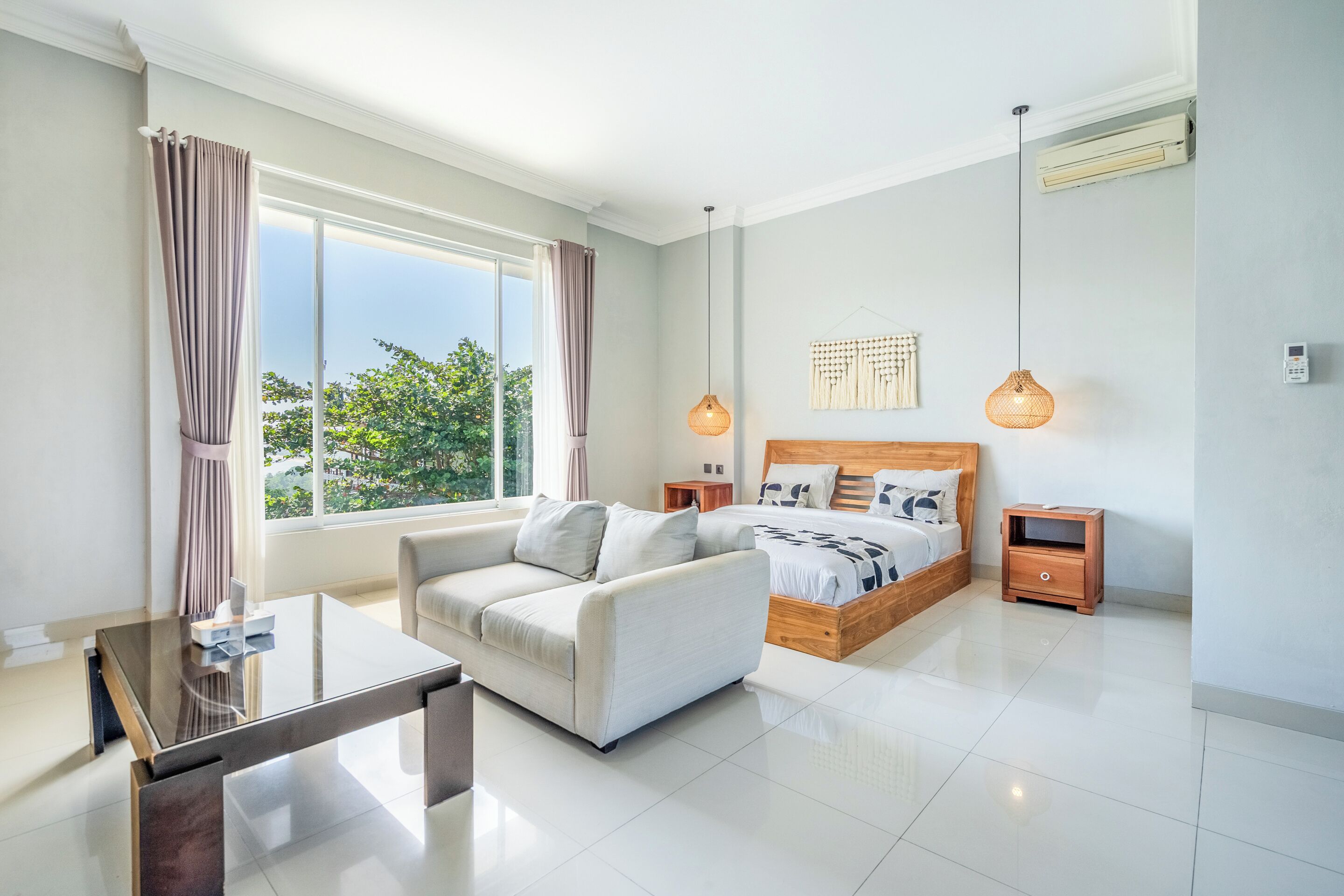 A modern bedroom with a bed, a sofa, a glass coffee table, and a bedside table.