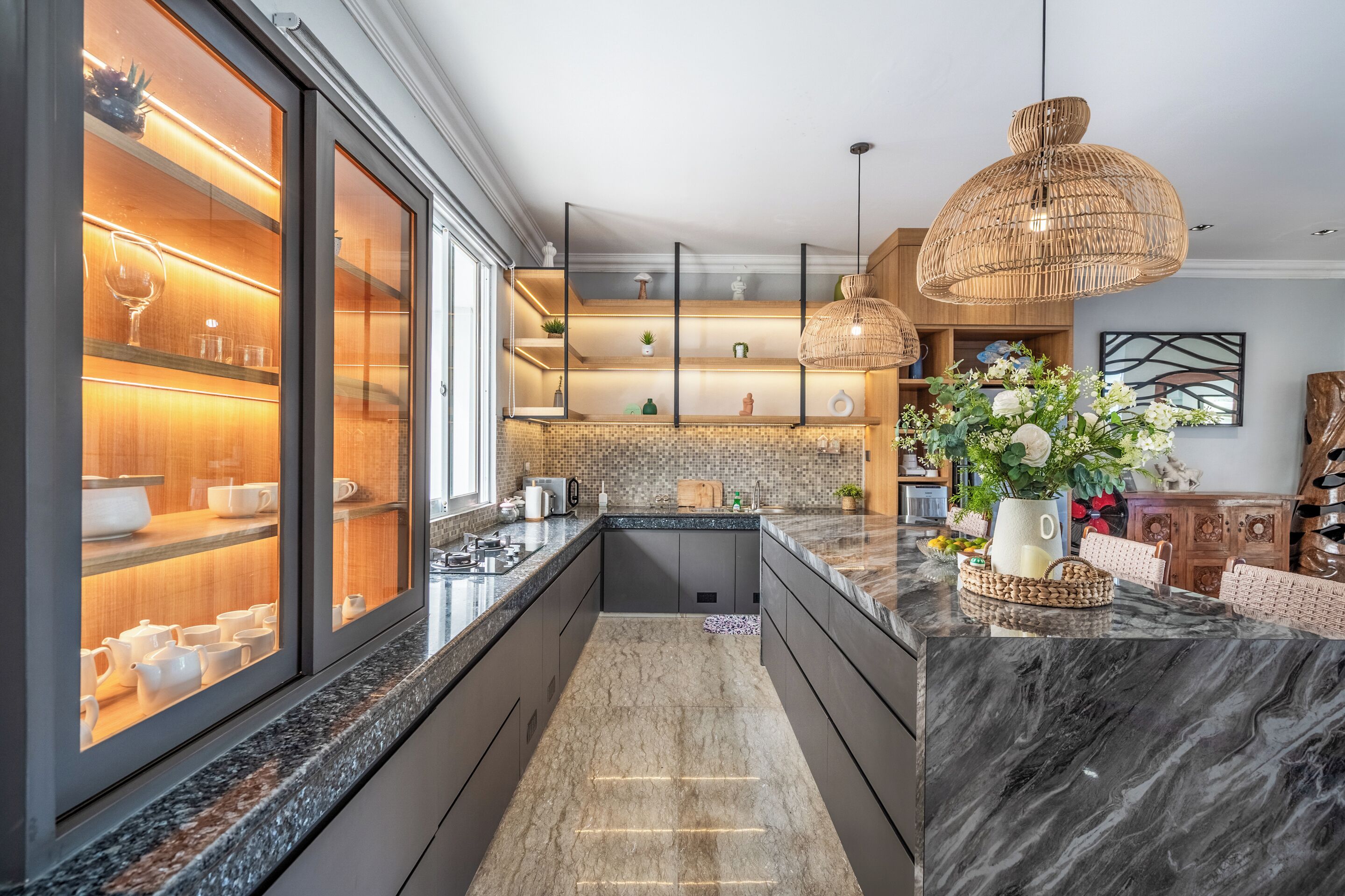 A modern kitchen with a marble countertop, built-in shelves, and a large window.