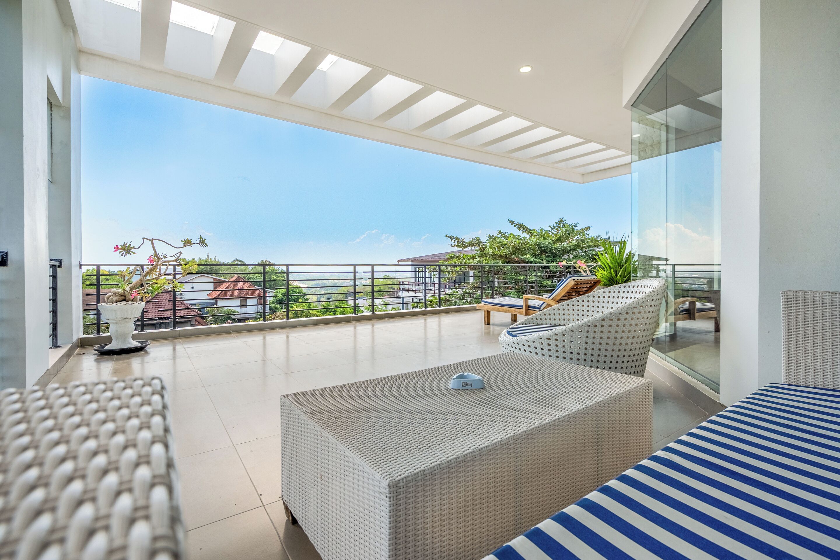 A modern balcony with wicker furniture, a potted plant, and a clear view of the surrounding area.