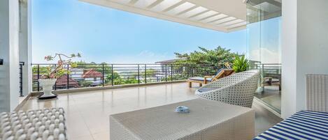 A modern balcony with wicker furniture, a potted plant, and a clear view of the surrounding area.