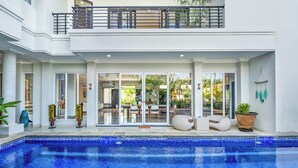 Et moderne hus med swimmingpool, store skydedøre og en balkon.