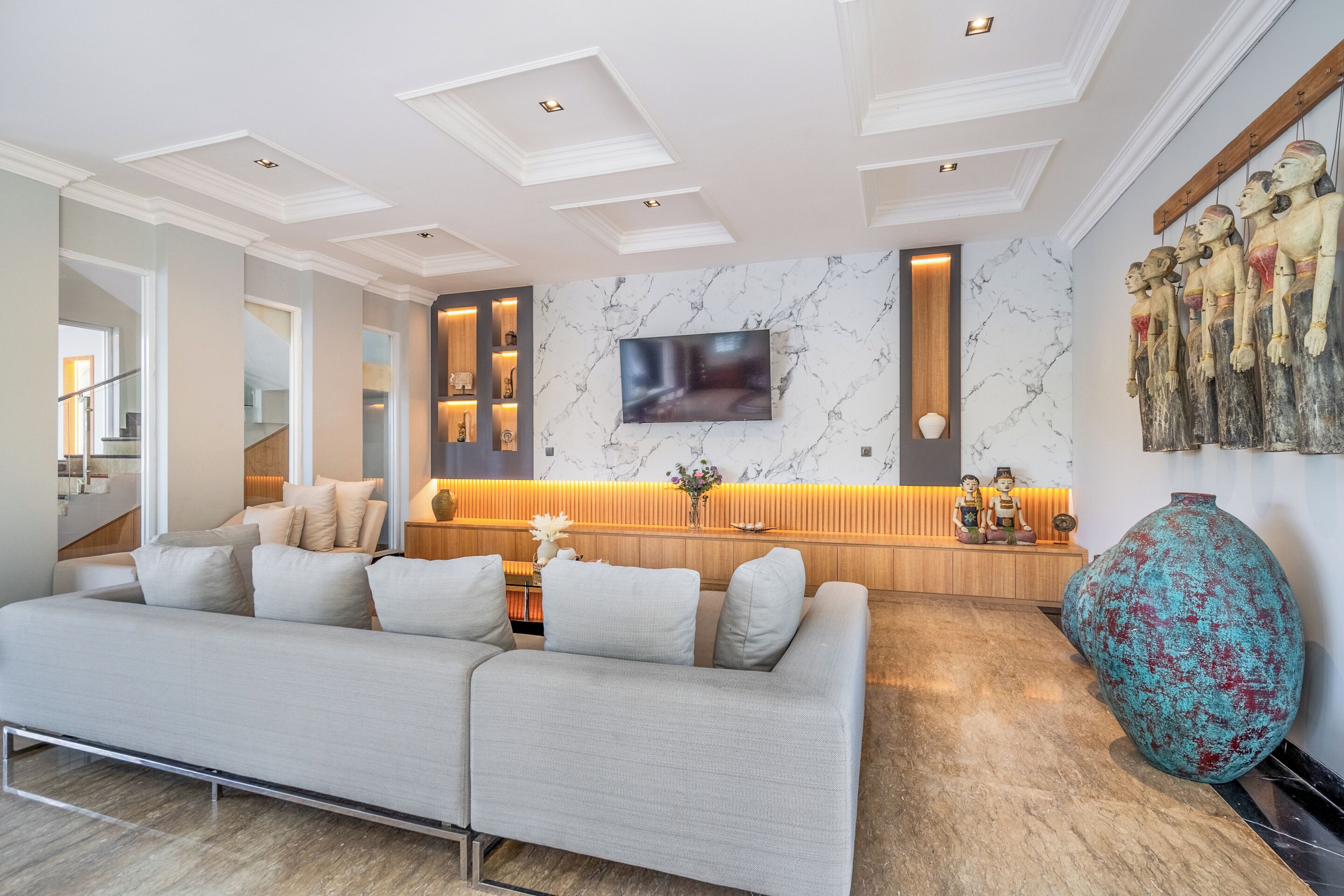A modern living room with a sofa, a TV, a wooden cabinet, and a large vase.